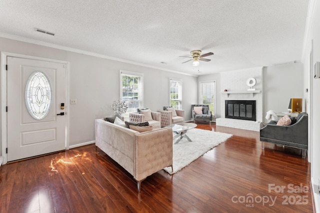 living area featuring visible vents, ceiling fan, plenty of natural light, and a textured ceiling