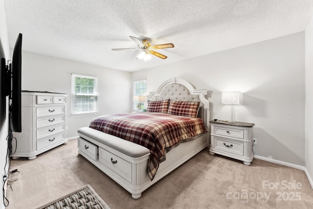 bedroom with ceiling fan, light colored carpet, baseboards, and a textured ceiling