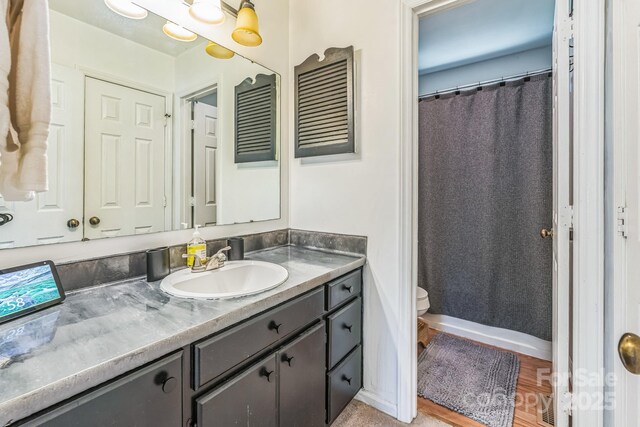 full bathroom with toilet, curtained shower, vanity, and wood finished floors