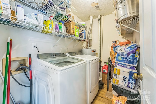 washroom featuring visible vents, laundry area, light wood finished floors, gas water heater, and washing machine and dryer