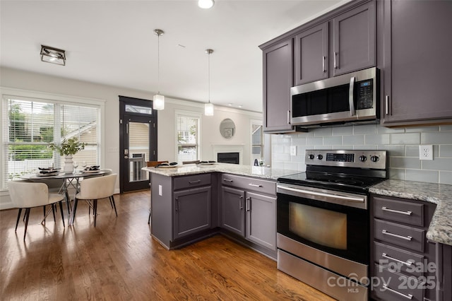 kitchen featuring stainless steel appliances, a peninsula, healthy amount of natural light, a fireplace, and recessed lighting