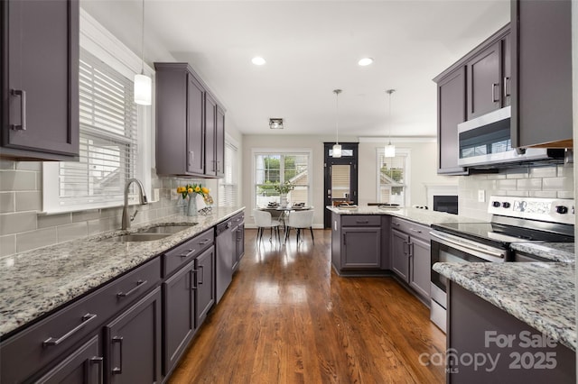 kitchen featuring stainless steel appliances, a sink, a peninsula, tasteful backsplash, and recessed lighting