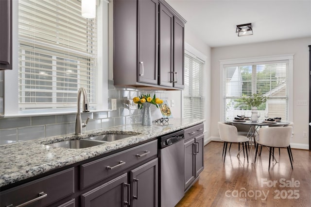 kitchen with dishwasher, a sink, backsplash, baseboards, and wood finished floors