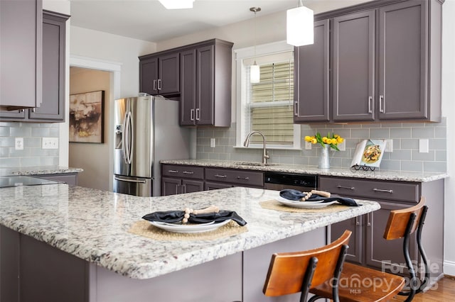 kitchen featuring a sink, appliances with stainless steel finishes, light stone countertops, and tasteful backsplash