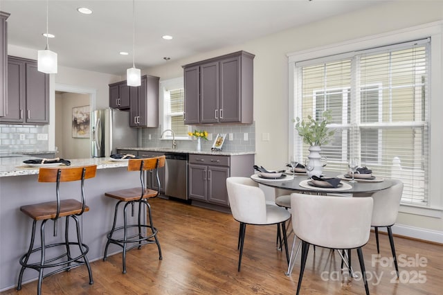 kitchen featuring stainless steel appliances, a kitchen breakfast bar, tasteful backsplash, dark wood-type flooring, and recessed lighting