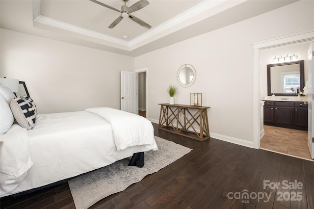 bedroom featuring crown molding, a raised ceiling, wood-type flooring, baseboards, and ensuite bathroom