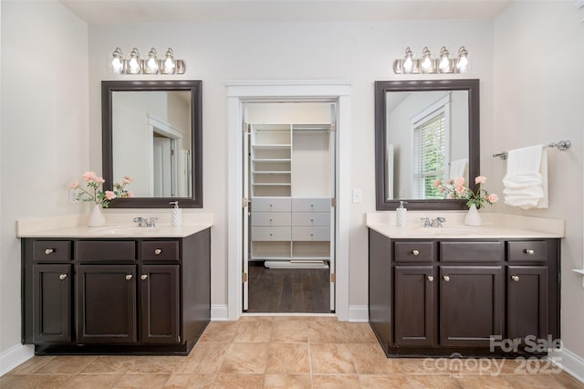 full bath with two vanities, baseboards, and a spacious closet