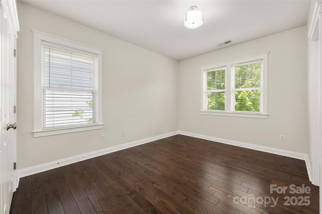 empty room with baseboards and dark wood-type flooring
