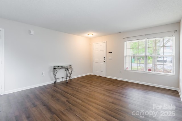 spare room with dark wood-type flooring and baseboards