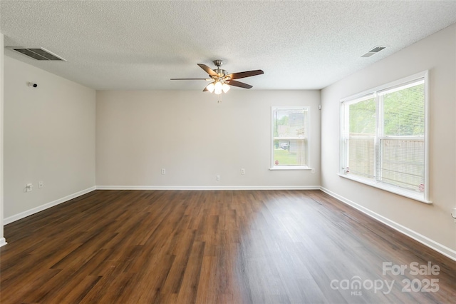 empty room with visible vents, a textured ceiling, and dark wood finished floors