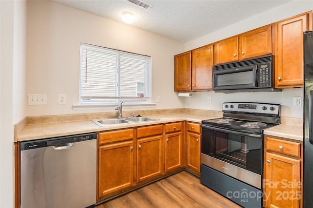 kitchen featuring light wood-style flooring, visible vents, light countertops, a sink, and stainless steel appliances