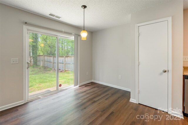 unfurnished room featuring visible vents, a textured ceiling, baseboards, and dark wood finished floors