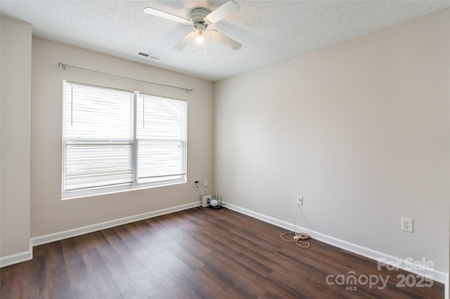 empty room featuring baseboards, visible vents, dark wood-style flooring, and a textured ceiling