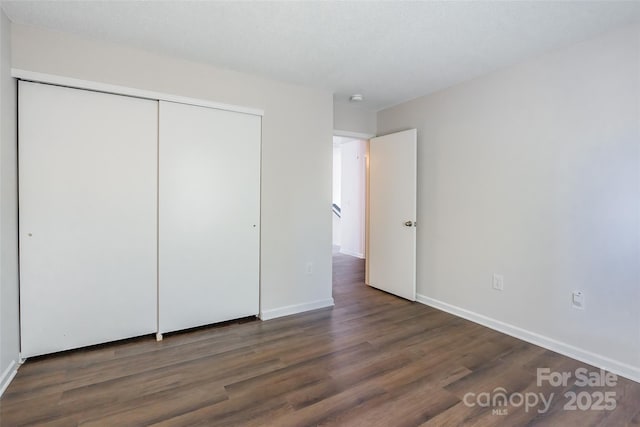 unfurnished bedroom featuring a closet, baseboards, and wood finished floors