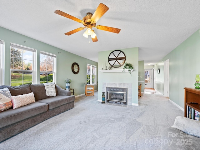 living area with baseboards, ceiling fan, carpet, a textured ceiling, and a fireplace