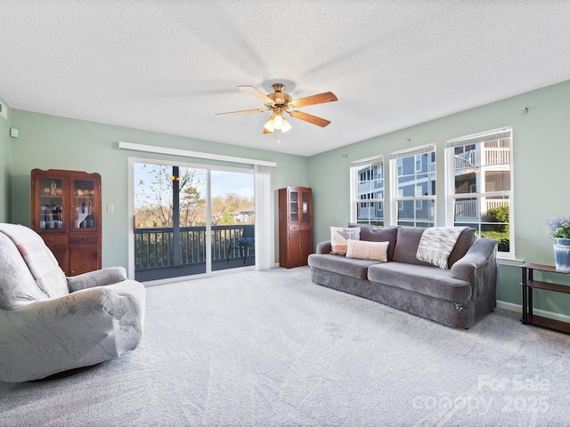 carpeted living area with a textured ceiling and a ceiling fan