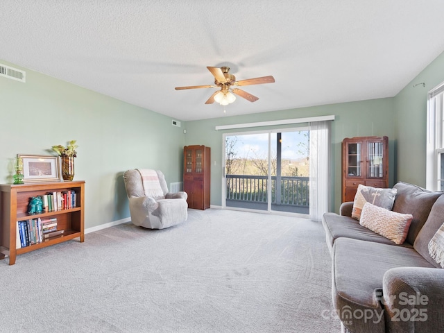 carpeted living room with visible vents, baseboards, and a ceiling fan