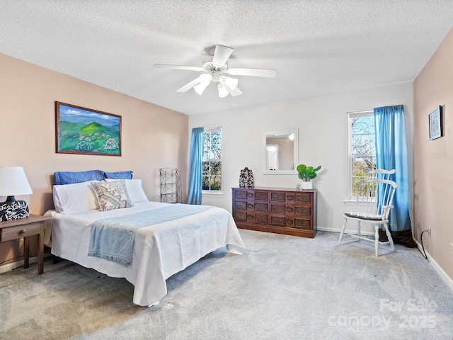 carpeted bedroom featuring a ceiling fan, a textured ceiling, baseboards, and multiple windows