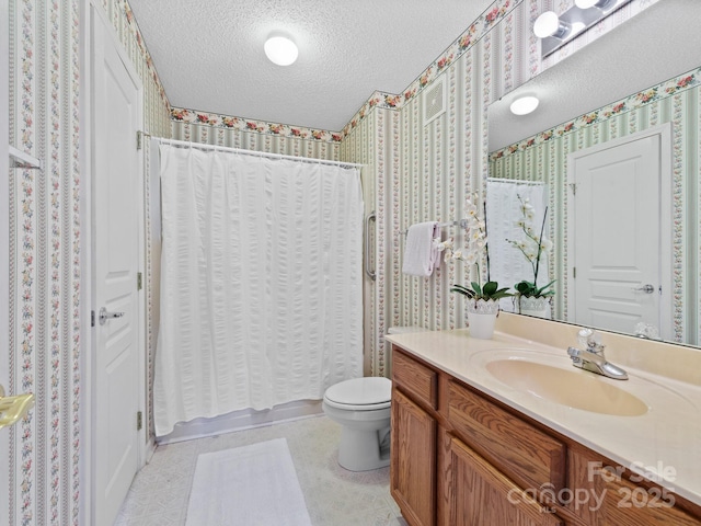 bathroom featuring vanity, a textured ceiling, wallpapered walls, and toilet