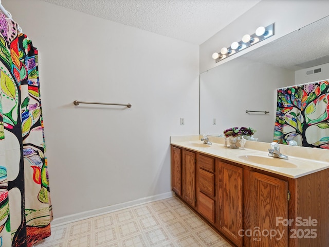 bathroom with double vanity, a textured ceiling, and a sink
