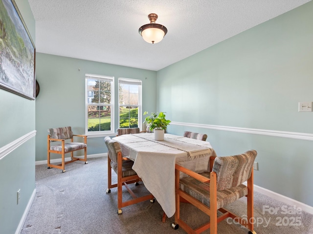 dining space featuring carpet floors, baseboards, and a textured ceiling