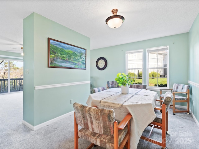 dining area featuring baseboards, carpet flooring, ceiling fan, and a textured ceiling