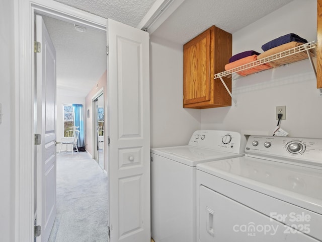 laundry area with cabinet space, independent washer and dryer, light carpet, and a textured ceiling