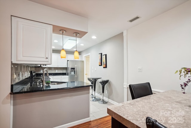7444 Hurstbourne Green Dr, Charlotte, NC 28277 - kitchen featuring white cabinets, visible vents, a sink, stainless steel fridge, and backsplash