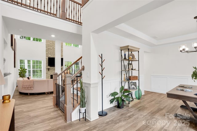interior space with stairway, a decorative wall, crown molding, wood finished floors, and a chandelier