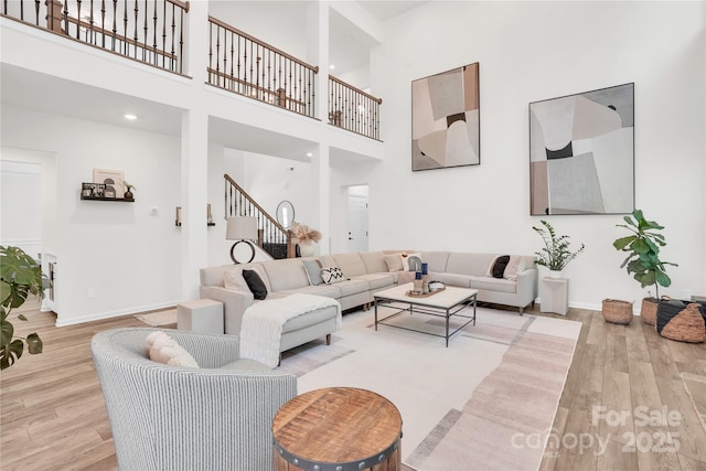 living area with wood finished floors, a high ceiling, baseboards, and stairway