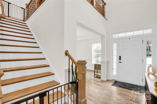 entrance foyer with a wealth of natural light, a towering ceiling, and light wood-style floors