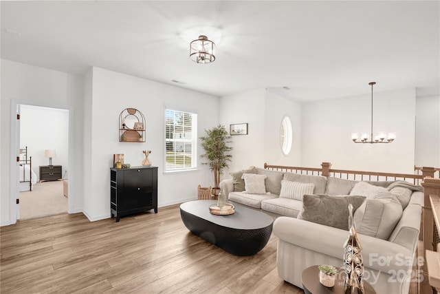 living area featuring light wood finished floors, baseboards, and an inviting chandelier