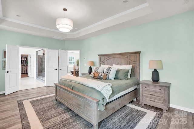 bedroom with a tray ceiling, light wood-style floors, and crown molding