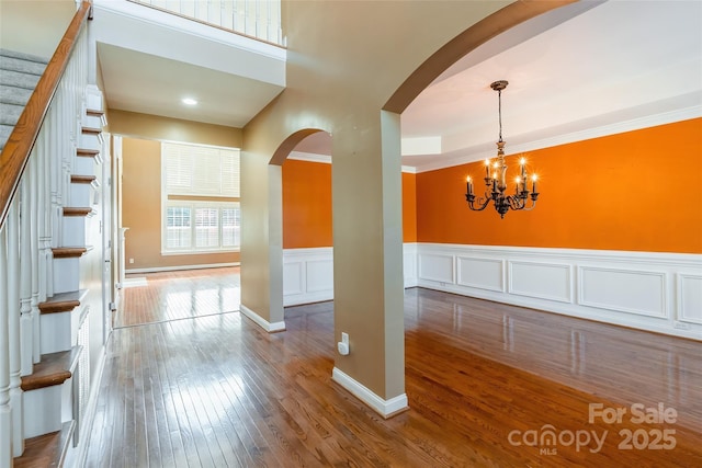 4333 Sawmill Trace Dr, Charlotte, NC 28213 - interior space featuring arched walkways, a notable chandelier, stairway, wood-type flooring, and a wainscoted wall