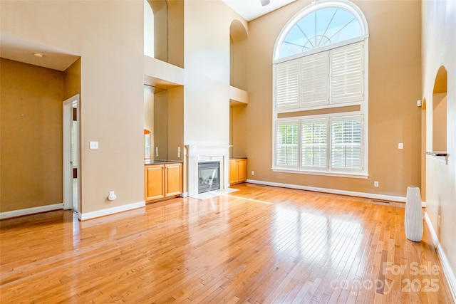 4333 Sawmill Trace Dr, Charlotte, NC 28213 - unfurnished living room with light wood-style flooring, a high ceiling, a fireplace with flush hearth, and baseboards