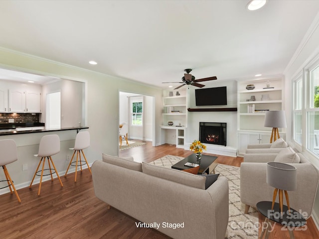915 Gate Rd, Monroe, NC 28112 - living room featuring healthy amount of natural light, crown molding, wood finished floors, ceiling fan, and a lit fireplace