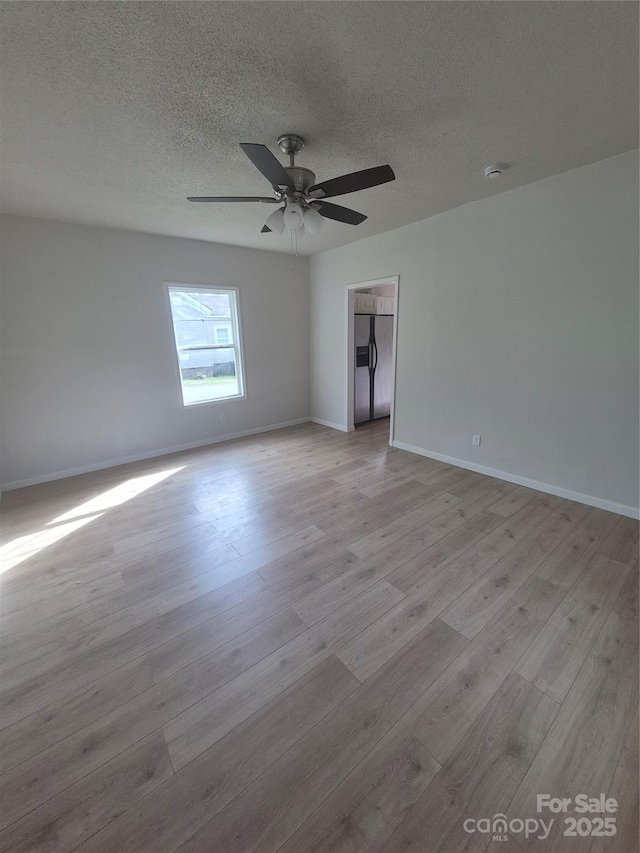 empty room featuring baseboards, a ceiling fan, a textured ceiling, and wood finished floors