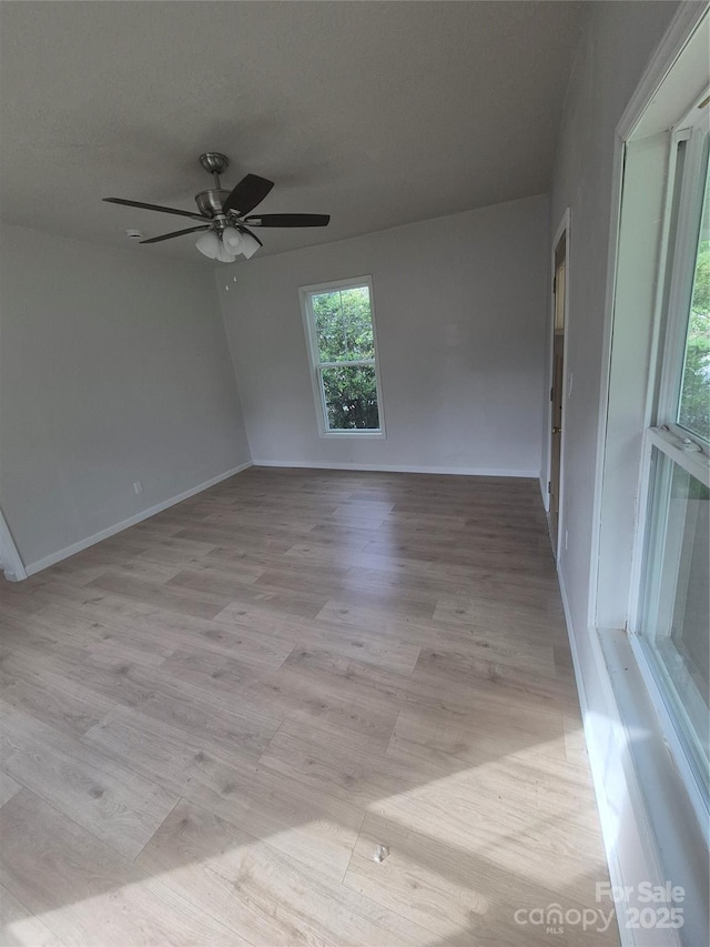 empty room featuring light wood-style floors, baseboards, and ceiling fan