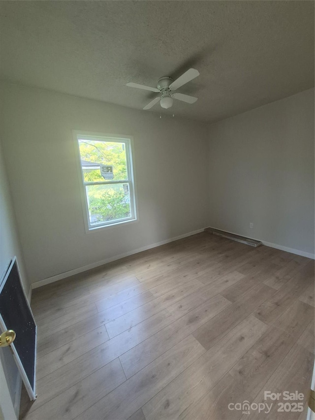 empty room with baseboards, ceiling fan, and light wood-type flooring