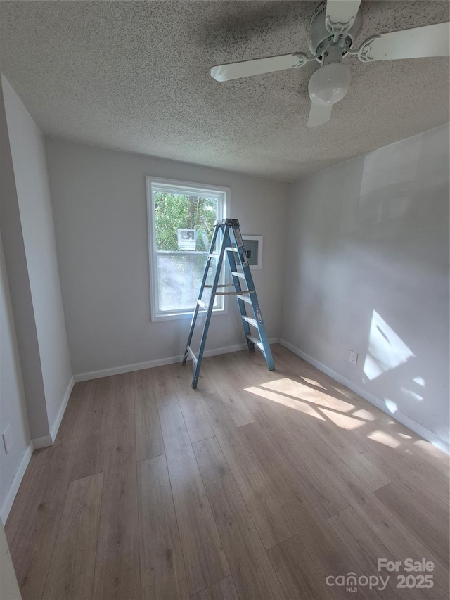spare room with baseboards, a ceiling fan, a textured ceiling, and wood finished floors