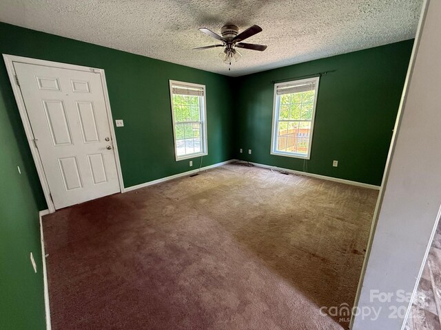 carpeted spare room with a textured ceiling, a ceiling fan, and baseboards