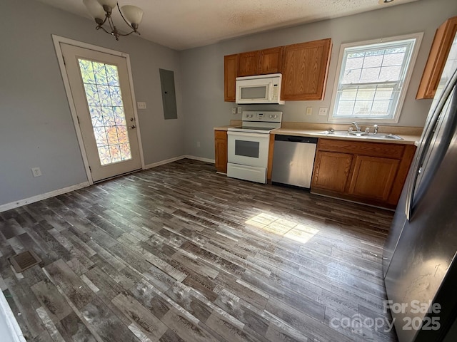 kitchen with stainless steel appliances, a sink, dark wood finished floors, light countertops, and a chandelier