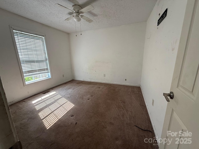spare room featuring carpet flooring, a textured ceiling, a ceiling fan, and baseboards