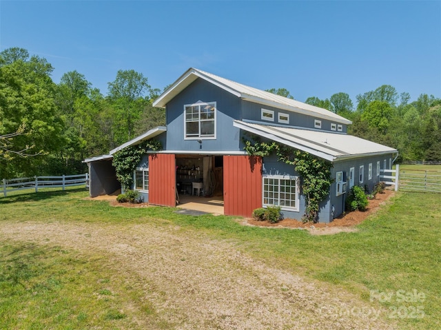 back of house with a lawn, fence, an outbuilding, and metal roof