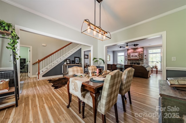 dining area with crown molding, stairs, light wood-style flooring, baseboards, and a notable chandelier