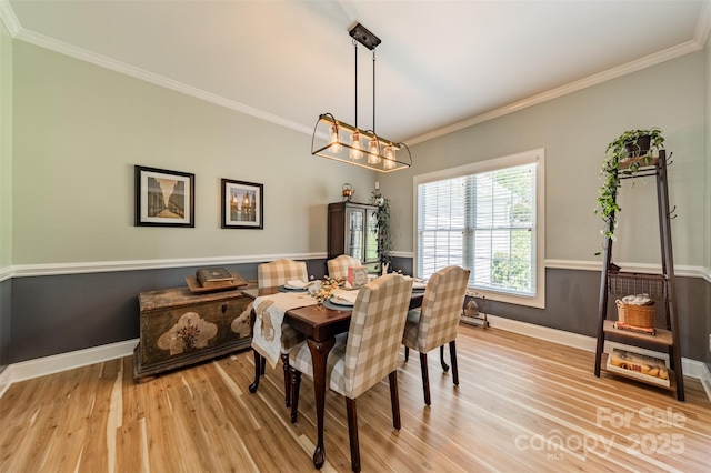 dining area with baseboards, ornamental molding, and light wood-type flooring