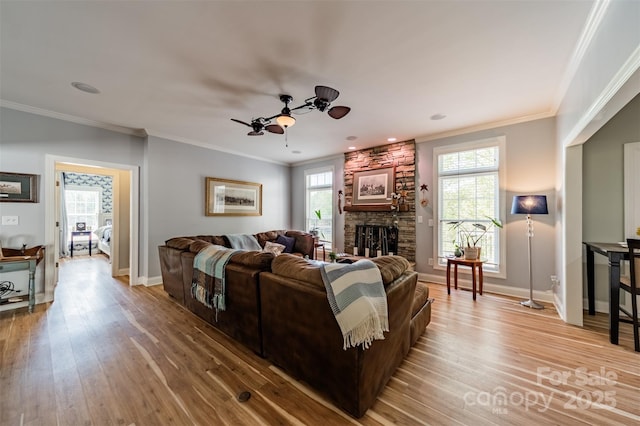 living room with light wood-type flooring, a ceiling fan, baseboards, and ornamental molding