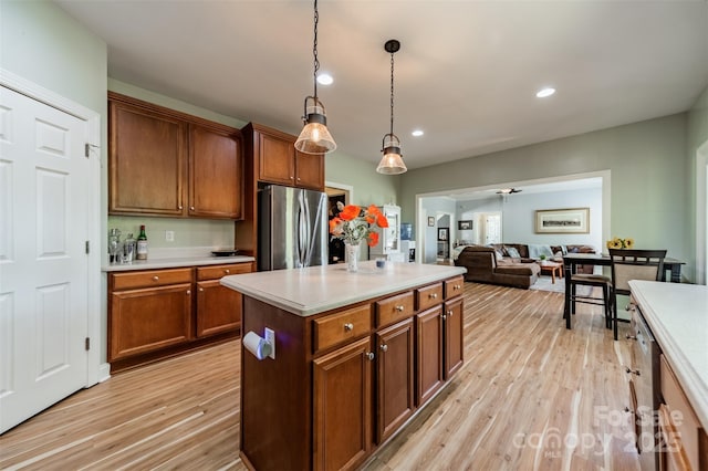 kitchen with light wood-style flooring, light countertops, appliances with stainless steel finishes, and hanging light fixtures