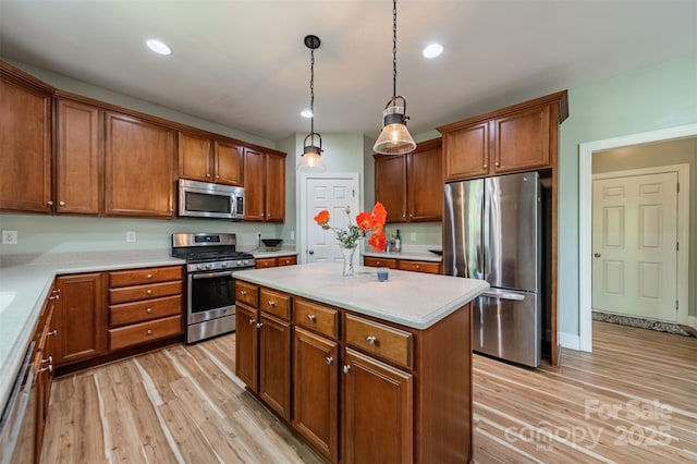 kitchen featuring brown cabinets, appliances with stainless steel finishes, a kitchen island, and light wood-type flooring
