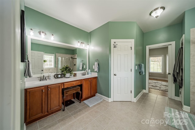 bathroom with tile patterned flooring, a sink, double vanity, and a stall shower